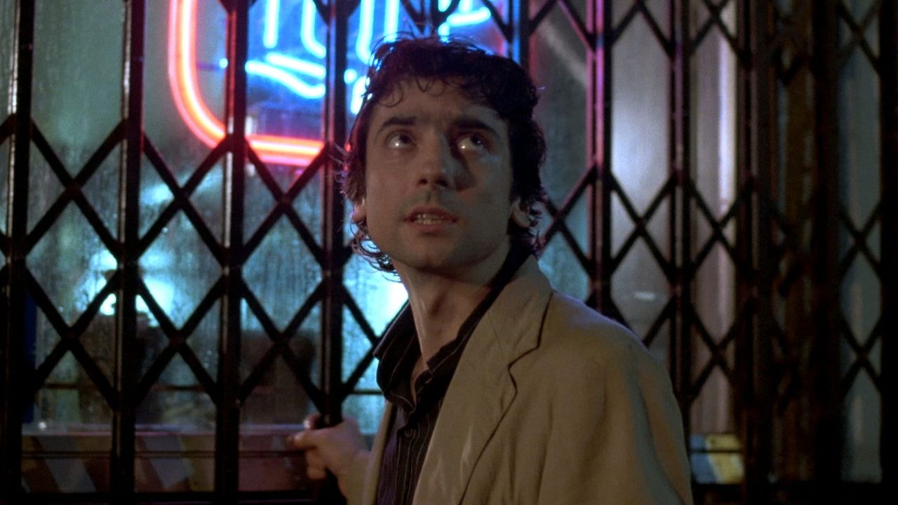 Griffin Dunne in front of a metal store gate